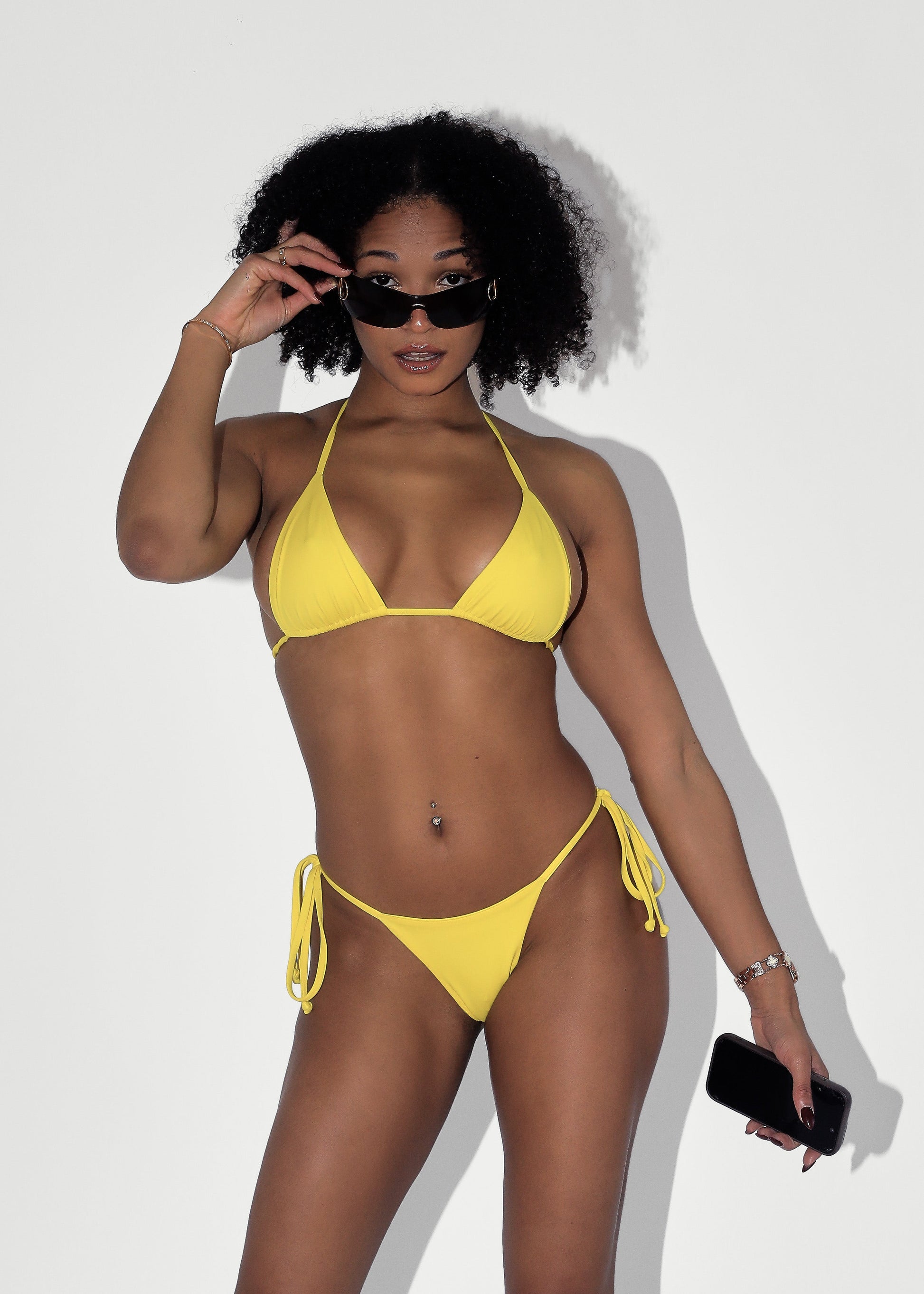 Woman in a yellow bikini posing against a white background